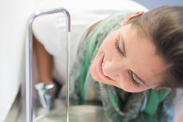 Junge Frau genießt Trinkwasser aus der Leitung.