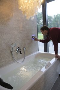 In der Badausstellung zeigt ein Fachmann einen Whirlpool für ein Komfortbad.
